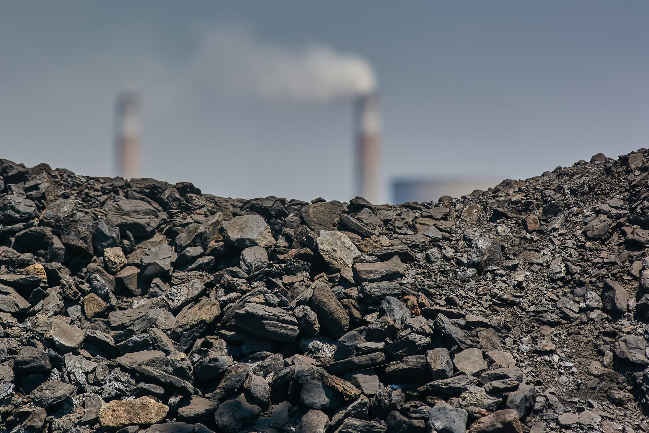 A Pile Of Coal By Smokestacks